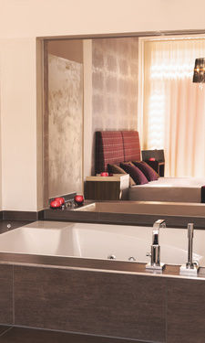 Luxuriöse Badewanne mit Blick auf das Doppelbett durch einen Spiegel