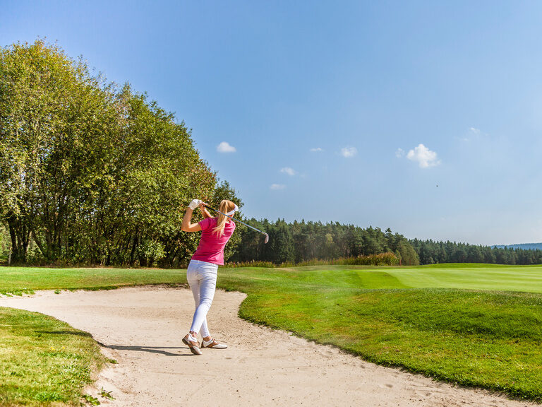 Frau spielt Golf auf großem Golfplatz
