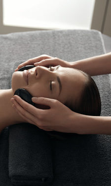 Liegende Frau bekommt Hot Stone Massage im Beauty- & Wellnessbereich im Bayerischer Wald