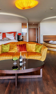 Luxus Suite mit Bett, bunter Couch und Whirlpool im Wellnesshotel Bayern